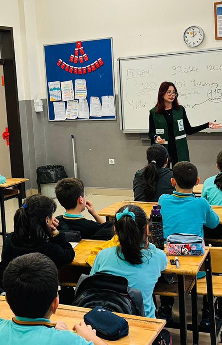 Arkadan çekilmiş bir karede, bir genç kadın ve üç genç adam yüksek bir tepede duruyor. Kollarını birbirlerinin omuzlarına ve bellerine dolamış bu grup, gün batımına karşı poz veriyor. Puslu fotoğrafın sol üst kısmında büyük puntolu küçük beyaz harflerle şu ifade yer alıyor: “Yeşilay gönüllüsü ol.” Devamında, küçük beyaz harflerle iki satır halinde şunlar yazıyor: “1920 yılında kurulan Yeşilay, değerli gönüllülerinin büyük destekleriyle insanlık için çalışmalarını ilk günkü heyecanıyla sürdürüyor.”